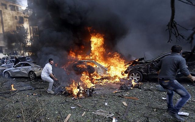 Lebanese men run to remove dead bodies from burned cars, at the scene where two explosions struck near the Iranian Embassy killing several, in Beirut, Lebanon on Tuesday November 19, 2013. (photo credit: AP/Hussein Malla) Lebanese men run to remove dead bodies from burned cars, at the scene where two explosions struck near the Iranian Embassy killing several, in Beirut, Lebanon on Tuesday November 19, 2013. (photo credit: AP/Hussein Malla)