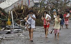 Residents cover their nose from the smell of dead bodies in Tacloban city, Leyte province central Philippines on Sunday, Nov. 10, 2013. Typhoon Haiyan, one of the strongest storms on record, slammed into six central Philippine provinces Friday leaving a wide swath of destruction and hundreds of people dead. (Photo credit: AP/Bullit Marquez)