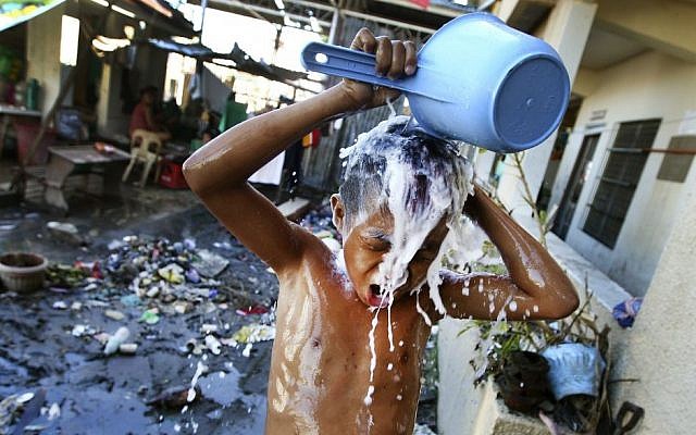A young Filipino takes a shower at a school turned into a temporary shelter for those affected by Typhoon Haiyan, in Tacloban, Philippines, Monday, November 18, 2013 (photo credit: AP/Dita Alangkara) A young Filipino takes a shower at a school turned into a temporary shelter for those affected by Typhoon Haiyan, in Tacloban, Philippines, Monday, November 18, 2013 (photo credit: AP/Dita Alangkara)