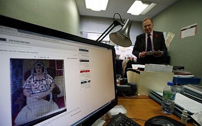 A picture on a news website, showing a painting by Henry Matisse entitled 'Sitzende Frau' ('Sitting Woman') which is part of the art recently found in Munich, Germany, as researchers of the Art Loss Register continue their work at their offices in central London, Wednesday, Nov. 6, 2013, with Julian Radcliffe, center, chairman of the Art Loss Register. (AP Photo/Lefteris Pitarakis)