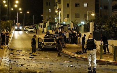 Bomb squad police unit examine the blackened remains of a car that exploded in a suspected bombing in the southern city of Ashkelon, Saturday night, November 2, 2013. (photo credit: David Buimovitch/Flash90)