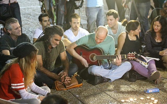 Dozens of Israelis, among them singer Mosh Ben-Ari (center, with dreadlocks), light candles and sing on Rabin Square in Tel Aviv, while mourning the death of Israeli singer-songwriter Arik Einstein, who passed away at the age of 74 on November 27, 2013 (photo credit: Flash90