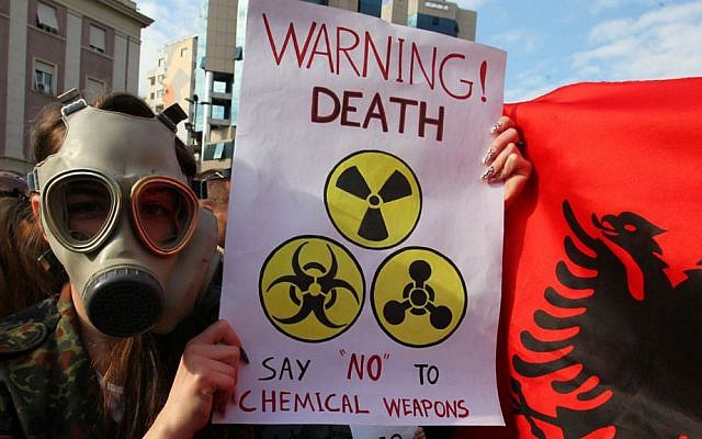 An Albanian student wears a gas mask and holds a sign during a protest against the dismantling of Syrian chemical weapons in Albania, in front of the prime minister's office in Tirana, on Thursday (AP/Hektor Pustina)