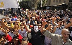 Supporters of Egypt's ousted president Mohammed Morsi chant anti-army slogans as one waves a national flag, during a protest in Cairo (photo credit: AP/Amr Nabil)