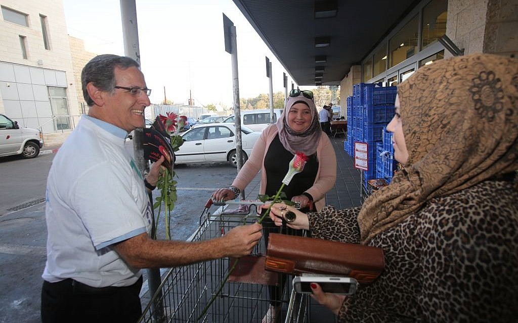 Yitzchak Glick offers a flower to a Palestinian shopper at the Rami Levi supermarket outside Alon Shvut in the West Bank, November 14, 2013 ( Yossi Zamir) Yitzchak Glick offers a flower to a Palestinian shopper at the Rami Levi supermarket outside Alon Shvut in the West Bank, November 14, 2013 ( Yossi Zamir)