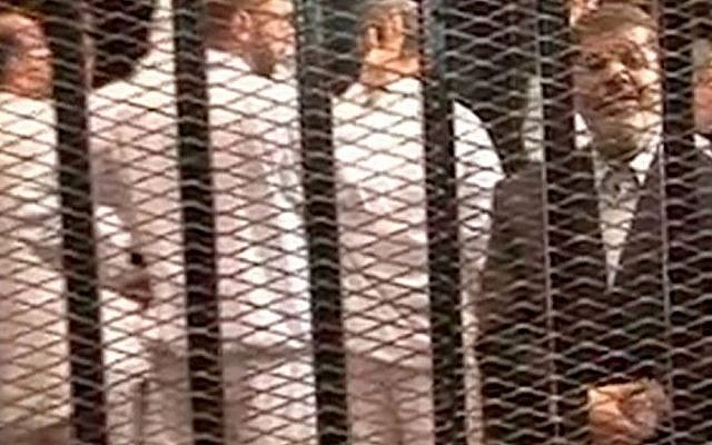 Image from video provided by Egypt's Interior Ministry shows ousted president Mohammed Morsi, right, speaking from the defendant's cage as he stands trial in Cairo, Nov. 4, 2013. (photo credit: AP/Egyptian Interior Ministry) Image from video provided by Egypt's Interior Ministry shows ousted president Mohammed Morsi, right, speaking from the defendant's cage as he stands trial in Cairo, Nov. 4, 2013. (photo credit: AP/Egyptian Interior Ministry)