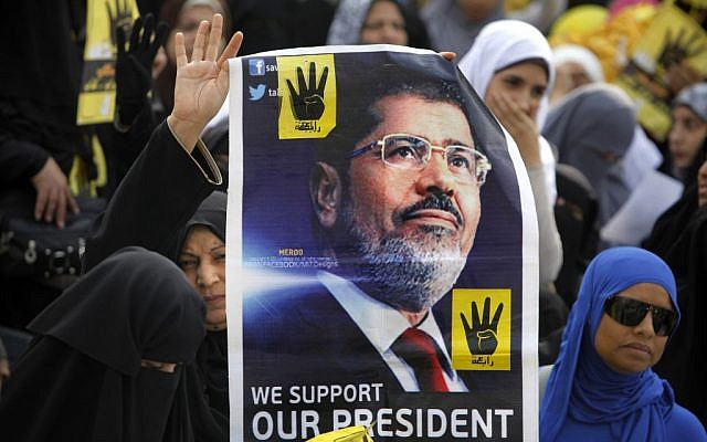 Supporters of Egypt's ousted president Mohammed Morsi raise his poster during a rally in Cairo, Egypt, on Nov. 8, 2013. The poster also shows four raised fingers, which has become a symbol of the Rabaah al-Adawiya mosque, where Morsi supporters had held a sit-in for weeks that was violently dispersed in August. (photo credit: AP/Amr Nabil) Supporters of Egypt's ousted president Mohammed Morsi raise his poster during a rally in Cairo, Egypt, on Nov. 8, 2013. The poster also shows four raised fingers, which has become a symbol of the Rabaah al-Adawiya mosque, where Morsi supporters had held a sit-in for weeks that was violently dispersed in August. (photo credit: AP/Amr Nabil)