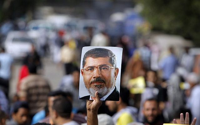 Supporters of Egypt's ousted President Mohammed Morsi raise his poster and their hands with four raised fingers, which has become a symbol of the Rabaah al-Adawiya mosque, where Morsi supporters had held a sit-in for weeks that was violently dispersed in August, during a protest in Cairo, Egypt, Friday, Nov. 8, 2013 (photo credit: AP/Amr Nabil) Supporters of Egypt's ousted President Mohammed Morsi raise his poster and their hands with four raised fingers, which has become a symbol of the Rabaah al-Adawiya mosque, where Morsi supporters had held a sit-in for weeks that was violently dispersed in August, during a protest in Cairo, Egypt, Friday, Nov. 8, 2013 (photo credit: AP/Amr Nabil)
