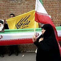 An Iranian woman walks past protesters holding an Iranian flag and photos of supreme leader Ayatollah Ali Khamenei during an annual anti-American demonstration in Tehran, Iran, Monday, Nov. 4, 2013 (photo credit: AP/Ebrahim Noroozi) An Iranian woman walks past protesters holding an Iranian flag and photos of supreme leader Ayatollah Ali Khamenei during an annual anti-American demonstration in Tehran, Iran, Monday, Nov. 4, 2013 (photo credit: AP/Ebrahim Noroozi)