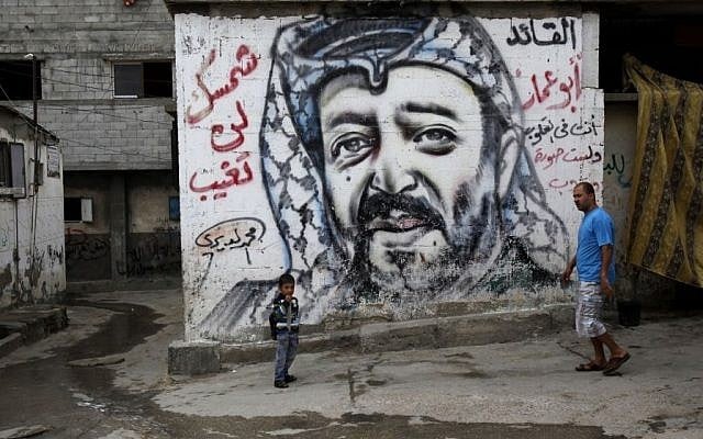 Palestinians walk past a mural depicting late Palestinian leader Yasser Arafat at the Shati Refugee Camp, in Gaza City, on November 7, 2013 (AP/Adel Hana) Palestinians walk past a mural depicting late Palestinian leader Yasser Arafat at the Shati Refugee Camp, in Gaza City, on November 7, 2013 (AP/Adel Hana)