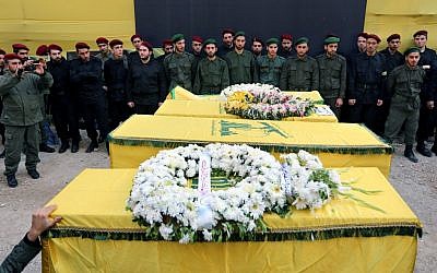 Hezbollah members stand near the coffins of four people, who were killed a day after two suicide bombings struck the Iranian Embassy in Beirut, during their funeral procession, in the southern suburb of Beirut, Lebanon, Wednesday, Nov. 20, 2013. (photo credit: AP/Bilal Hussein) 