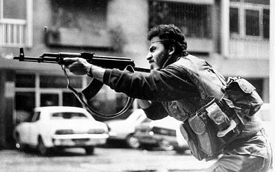 A Shiite Muslim AMAL militiaman fires his AK-47 assault rifle during skirmishes with Druse irregulars on Corniche Mazraa road, West Beirut, Lebanon, Feb. 20, 1987.  (photo credit: AP, File)