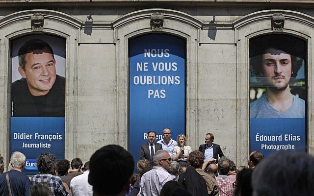 In this file photo taken Tuesday July 9, 2013, Florence Aubenas, holding a microphone at center, a French journalist who was held hostage in Iraq, delivers her speech during a gathering for Europe-1 radio reporter Didier Francois, on the banner at left, and independent photographer Edouard Elias at Europe I radio headquarters in Paris. They have been missing in Syria since the summer. (Photo credit: AP/Remy de la Mauviniere, File) In this file photo taken Tuesday July 9, 2013, Florence Aubenas, holding a microphone at center, a French journalist who was held hostage in Iraq, delivers her speech during a gathering for Europe-1 radio reporter Didier Francois, on the banner at left, and independent photographer Edouard Elias at Europe I radio headquarters in Paris. They have been missing in Syria since the summer. (Photo credit: AP/Remy de la Mauviniere, File)