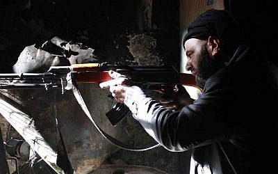 A Free Syrian Army fighter aims his AK-47 as he takes his battle position in Aleppo, Syria. (Photo credit: AP/Aleppo Media Center AMC, File)
