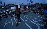 Typhoon Haiyan survivors walk through the ruins of their neighborhood in Tacloban, central Philippines on Wednesday, Nov. 13, 2013. (Photo credit: AP/David Guttenfelder)