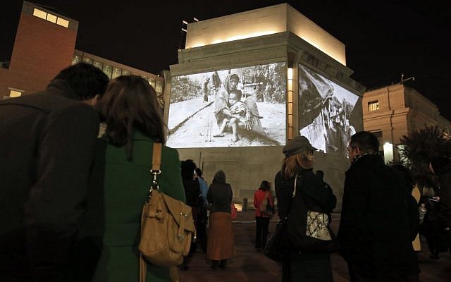 People look at photographs by Greg Constantine showing the plight of Burma's Rohingya people, projected on the exterior walls of the United States Holocaust Memorial Museum in Washington, Monday, Nov. 4, 2013. (photo credit: AP Photo/Alex Brandon)