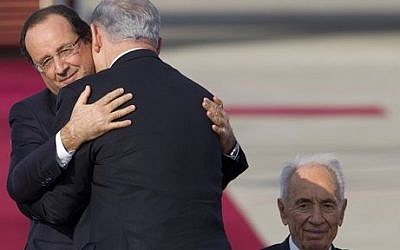 French President Francois Hollande, left, hugs Israel's Prime Minister Benjamin Netanyahu as Israel's President Shimon Peres watches on, upon Hollande's arrival in Ben Gurion airport near Tel Aviv, Sunday, November 17, 2013 (photo credit: AP/Ariel Schalit)