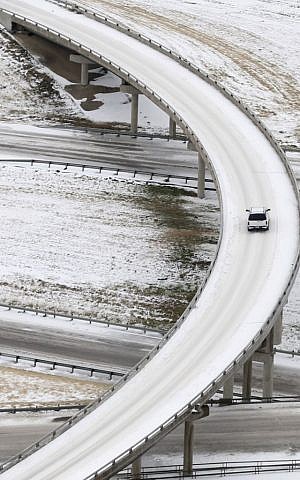 A lone vehicle is seen navigating icy road conditions in Denton, Texas, on Saturday, December 7, 2013, (photo credit: AP Photo/Tony Gutierrez) A lone vehicle is seen navigating icy road conditions in Denton, Texas, on Saturday, December 7, 2013, (photo credit: AP Photo/Tony Gutierrez)