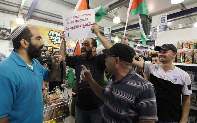 Palestinian protesters hold up flags and a sign reading "boycott occupation and its products" during a protest at a Rami Levy supermarket in the West Bank Jewish settlement of Modiin Illit, October 24, 2012 (photo credit: Issam Rimawi/Flash90) Palestinian protesters hold up flags and a sign reading "boycott occupation and its products" during a protest at a Rami Levy supermarket in the West Bank Jewish settlement of Modiin Illit, October 24, 2012 (photo credit: Issam Rimawi/Flash90)