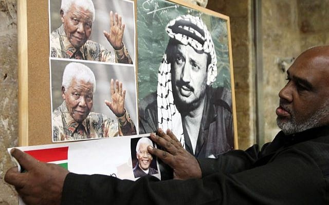 A Palestinian man hangs a picture of Nelson Mandela next to a portrait of Yasser Arafat at a memorial service in Jerusalem's Old City, December 8, 2013 (photo credit: Sliman Khader/Flash90) A Palestinian man hangs a picture of Nelson Mandela next to a portrait of Yasser Arafat at a memorial service in Jerusalem's Old City, December 8, 2013 (photo credit: Sliman Khader/Flash90)