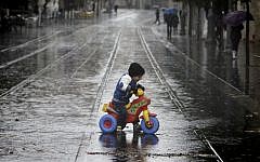 A toddler rides a tricycle through puddles on Jaffa Road in Jerusalem, Wednesday, December 11, 2013 (photo credit: Miriam Alster/Flash90)