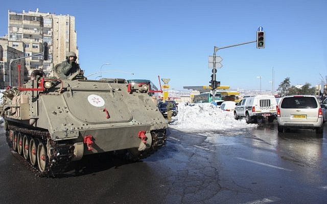 An IDF armored personnel carrier is seen clearing a snow-covered street in Jerusalem after a major snow storm hit the city over the weekend, December 15, 2013 (photo credit: Meital Cohen/Flash90)