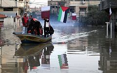 Palestinians take a boat through flooded streets in Gaza City, December 17, 2013 (photo credit: Wissam Nassar/Flash90)