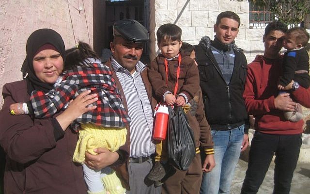 Standing outside their Hebron home before leaving for Holon, (from left), Lubna Abu Danash holding her daughter Shuruk, Mahmoud Abu Danash holding Muath, and his older brothers. (photo credit: Ilan Ben Zion/Times of Israel staff)
