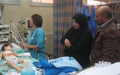 Mahmoud Abu Danash (right) and his wife Lubna stand beside the bed of their son, Muath, in the ICU at Holon's Wolfson Medical Center on Wednesday, December 25, 2013. (photo credit: Ilan Ben Zion/Times of Israel staff)