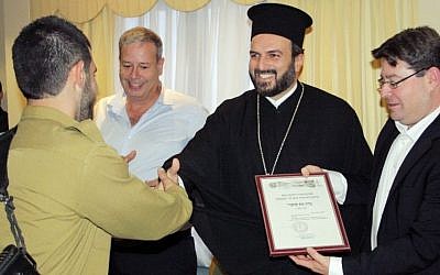 A Christian Arab soldier receiving a certificate of appreciation from Greek Orthodox priest Gabriel Naddaf during a 2013 event in Nazareth (photo credit: courtesy IDF Spokesperson's Unit)