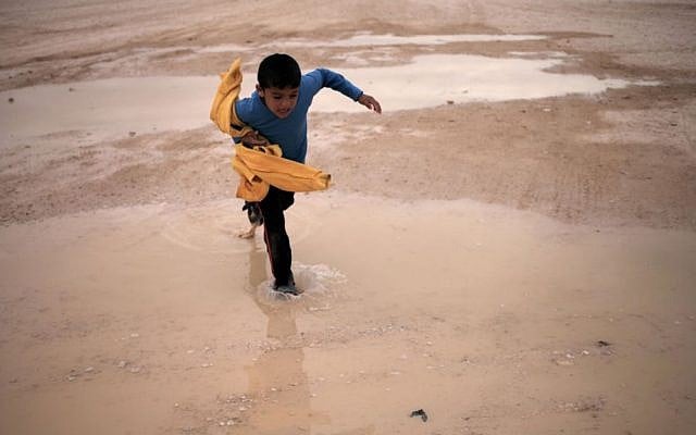 A Syrian boy crosses a water puddle at the Zaatari refugee camp, in Mafraq, Jordan, on Tuesday (photo credit: AP/Mohammad Hannon) A Syrian boy crosses a water puddle at the Zaatari refugee camp, in Mafraq, Jordan, on Tuesday (photo credit: AP/Mohammad Hannon)