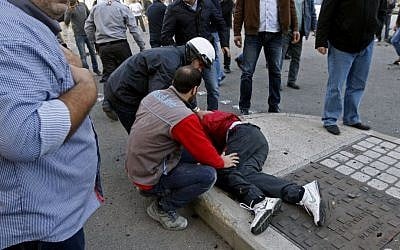 In this Friday, Dec. 27, 2013 photo, a Lebanese policeman helps 16-year-old Mohammed Shaar, who was mortally wounded at the scene after a car bomb explosion in Beirut, Lebanon. (AP Photo)