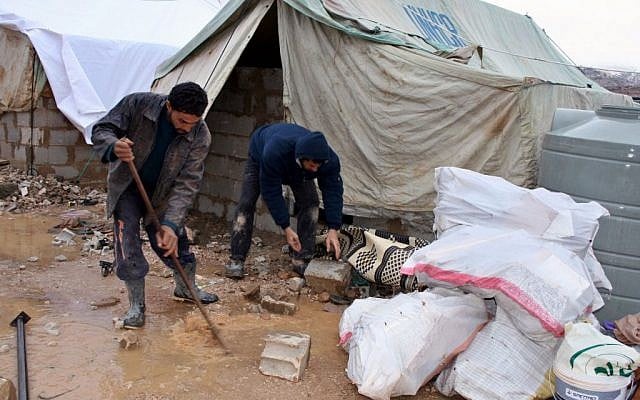 Syrian refugees secure their tent with stones and remove water around their tent as a heavy snowstorm batters the region, in a camp for Syrians who fled their country’s civil war, in the Bekaa valley, eastern Lebanon, Wednesday, Dec. 11, 2013. (Photo credit: AP/Shibli Abi-Assi) Syrian refugees secure their tent with stones and remove water around their tent as a heavy snowstorm batters the region, in a camp for Syrians who fled their country’s civil war, in the Bekaa valley, eastern Lebanon, Wednesday, Dec. 11, 2013. (Photo credit: AP/Shibli Abi-Assi)