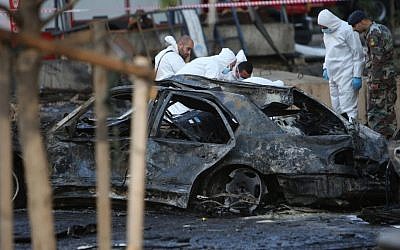 Lebanese army investigators in white coveralls inspect the scene of an explosion in central Beirut, Lebanon, Friday, Dec. 27, 2013, in which Mohammad Chatah, a senior aide to former Lebanese Prime Minister Saad Hariri, was killed. (Photo credit: AP/Hussein Malla)