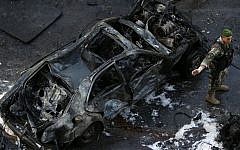 A Lebanese Army soldier stands next to a destroyed car at the scene of an explosion in central Beirut, Lebanon, Friday, Dec. 27, 2013, in which Mohammad Chatah, a senior aide to former Lebanese prime minister Saad Hariri, was killed. (photo credit: AP/Hussein Malla)
