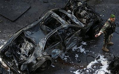 A Lebanese Army soldier stands next to a destroyed car at the scene of an explosion in central Beirut, Lebanon, Friday, Dec. 27, 2013, in which Mohammad Chatah, a senior aide to former Lebanese prime minister Saad Hariri, was killed. (photo credit: AP/Hussein Malla)
