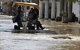 Palestinians ride a donkey cart to cross a flooded area following heavy rains in Gaza City, Friday, Dec. 13, 2013. (Photo credit: AP/Adel Hana)