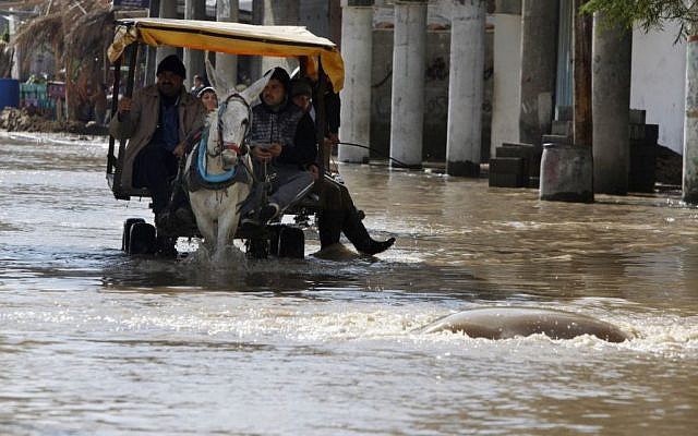 Palestinians ride a donkey cart to cross a flooded area following heavy rains in Gaza City, Friday, Dec. 13, 2013. (Photo credit: AP/Adel Hana) Palestinians ride a donkey cart to cross a flooded area following heavy rains in Gaza City, Friday, Dec. 13, 2013. (Photo credit: AP/Adel Hana)