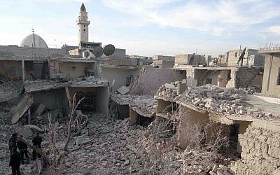 Syrian citizens stand on the rubble of houses that were destroyed by government airstrikes in Aleppo, Syria, Wednesday, Dec. 18, 2013 (photo credit: AP/Aleppo Media Center AMC)