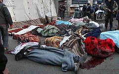 Syrians stand near the bodies of people who were killed by a Syrian government airstrike outside a field hospital in Aleppo, Syria, on December 15, 2013. (photo credit: AP/Aleppo Media Center)