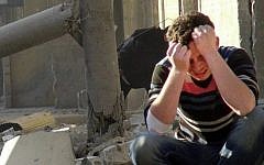 A Syrian man mourns as he sits in the rubble of buildings following a Syrian government airstrike in Aleppo, Syria. (Photo credit: AP Photo/Aleppo Media Center AMC)