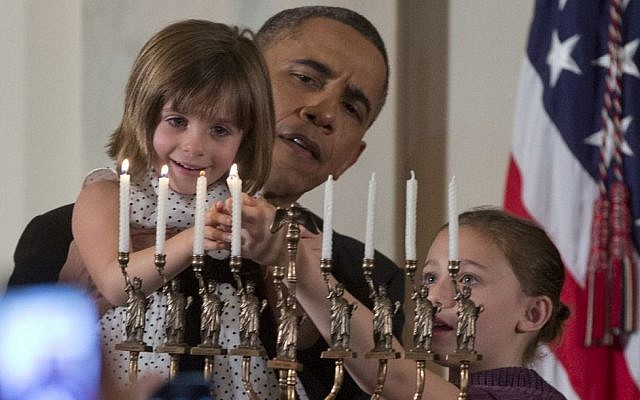 President Barack Obama holds up Kylie Schmitter as she, alongside her sister Lainey Schmitter, lights the menorah during the first of two Hanukkah receptions in the White House, on Thursday, December 5, 2013. (photo credit: AP/Carolyn Kaster) President Barack Obama holds up Kylie Schmitter as she, alongside her sister Lainey Schmitter, lights the menorah during the first of two Hanukkah receptions in the White House, on Thursday, December 5, 2013. (photo credit: AP/Carolyn Kaster)