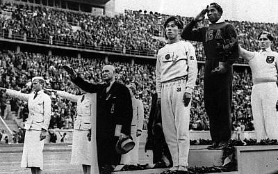 Gold medalist Jesse Owens of the United States salutes as others perform the Nazi salute at the Summer Olympics in Berlin, August 11, 1936. (AP Photo/File)