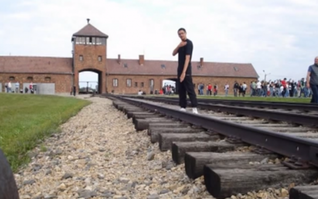 A young man displays the quenelle in front of the main gate of the Auschwitz-Birkenau death camp (photo credit: YouTube screenshot) A young man displays the quenelle in front of the main gate of the Auschwitz-Birkenau death camp (photo credit: YouTube screenshot)
