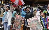 People hold images of former South African president Nelson Mandela ahead of his memorial service at the FNB Stadium in Soweto, near Johannesburg, South Africa, Tuesday Dec. 10, 2013. (Photo credit: AP/Bernat Armangue)