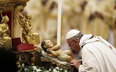 Pope Francis kisses a statue of baby Jesus as he celebrates the Christmas Eve Mass in St. Peter's Basilica at the Vatican, Tuesday, Dec. 24, 2013 (photo credit: AP/Gregorio Borgia)