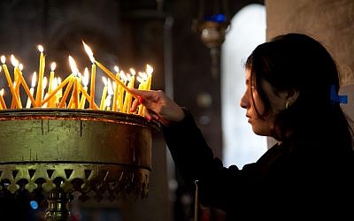 A girl lights candles in Bethlehem's Church of the Nativity (Nativity candles photo via Shutterstock)