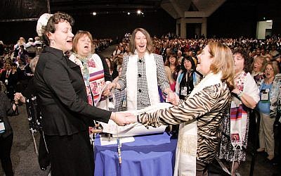 A group of women hold hands around the Torah during the Shabbat morning service at the Union for Reform Judaism's biennial conference in San Diego, December 14, 2013. (URJ via JTA)