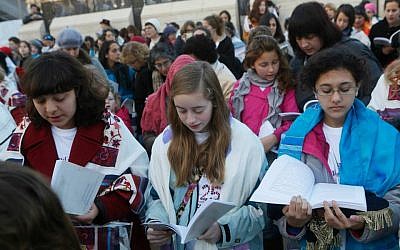 Eliza Moss-Horwitz, Lucy Sattler and Alexandra Schwartz pray with Women of the Wall. Schwartz (right) holds an empty Torah cover beneath her prayer book, symbolizing the Torah scroll the group was prevented from bringing in to the Kotel plaza, January 2014. (photo credit: Courtesy of Moving Traditions)