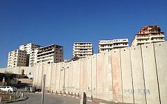 Apartment buildings in Ras Khamis peek over the security barrier in East Jerusalem (photo credit: Elhanan Miller/Times of Israel)